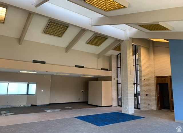 Lobby featuring high vaulted ceiling, brick wall, and beamed ceiling