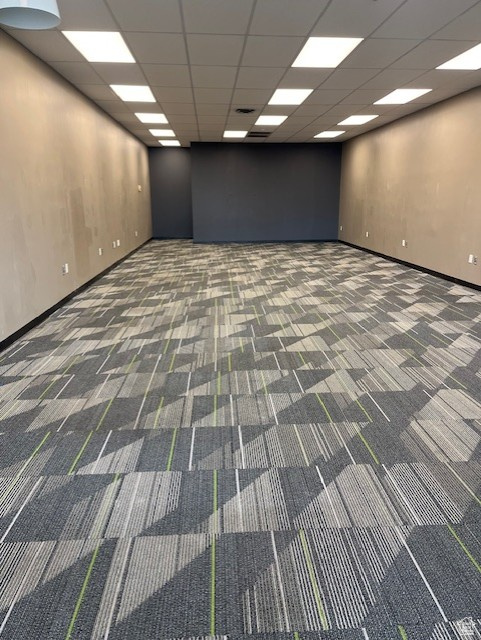 Spare room featuring carpet, baseboards, and a paneled ceiling