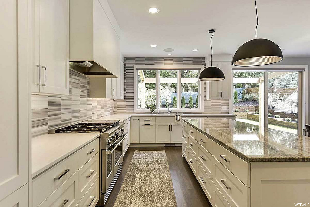 kitchen with hardwood floors, natural light, stainless steel finishes, extractor fan, gas range oven, white cabinetry, light countertops, and pendant lighting