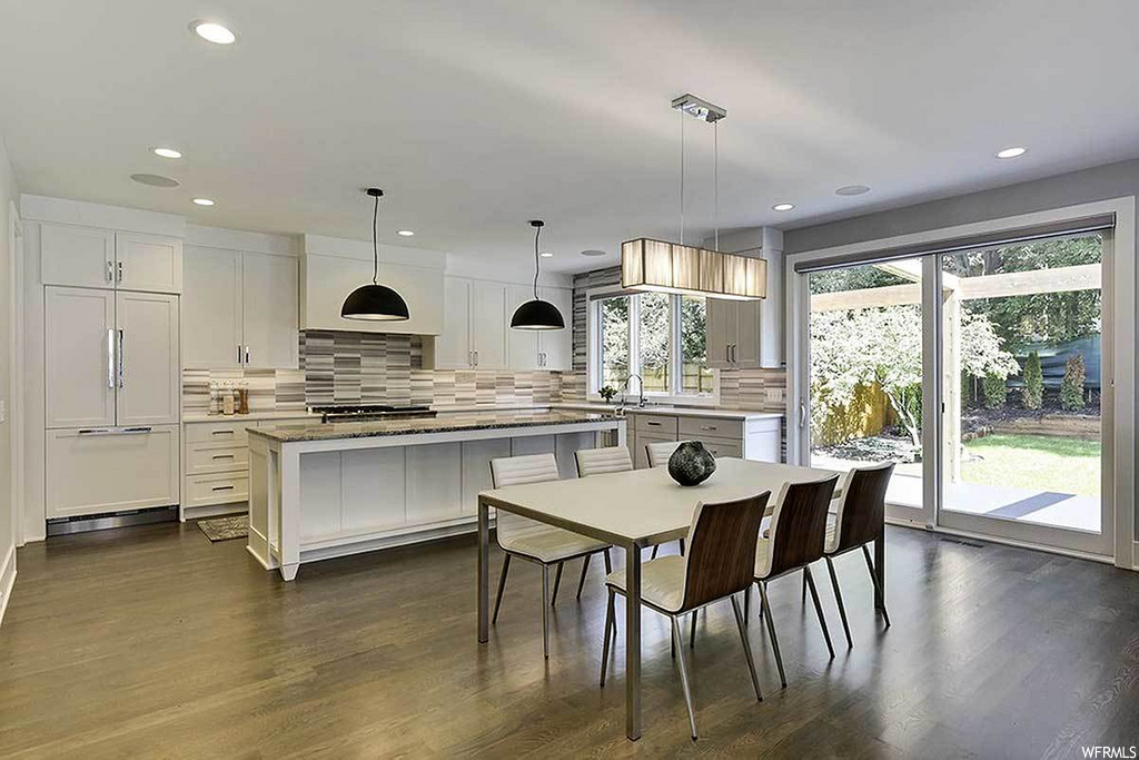 interior space with a center island, natural light, hardwood flooring, white cabinetry, light countertops, and pendant lighting