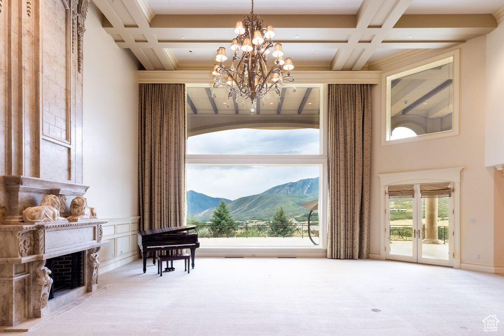 Living area with a notable chandelier, light carpet, beam ceiling, coffered ceiling, and a mountain view