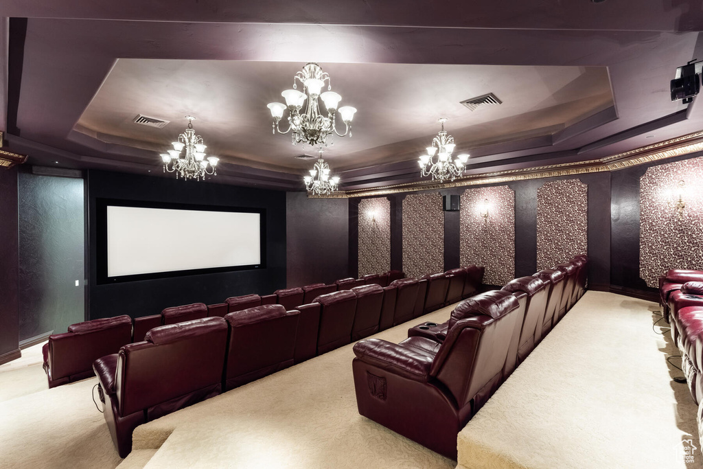 Carpeted home theater room featuring an inviting chandelier and a tray ceiling