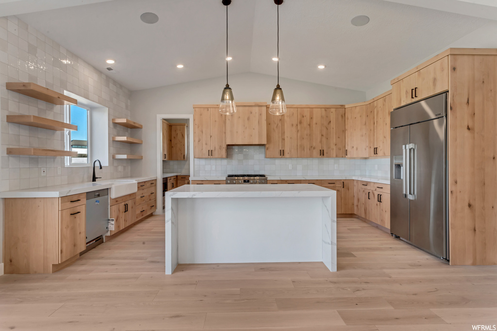 Kitchen featuring lofted ceiling, a center island, tasteful backsplash, and stainless steel appliances