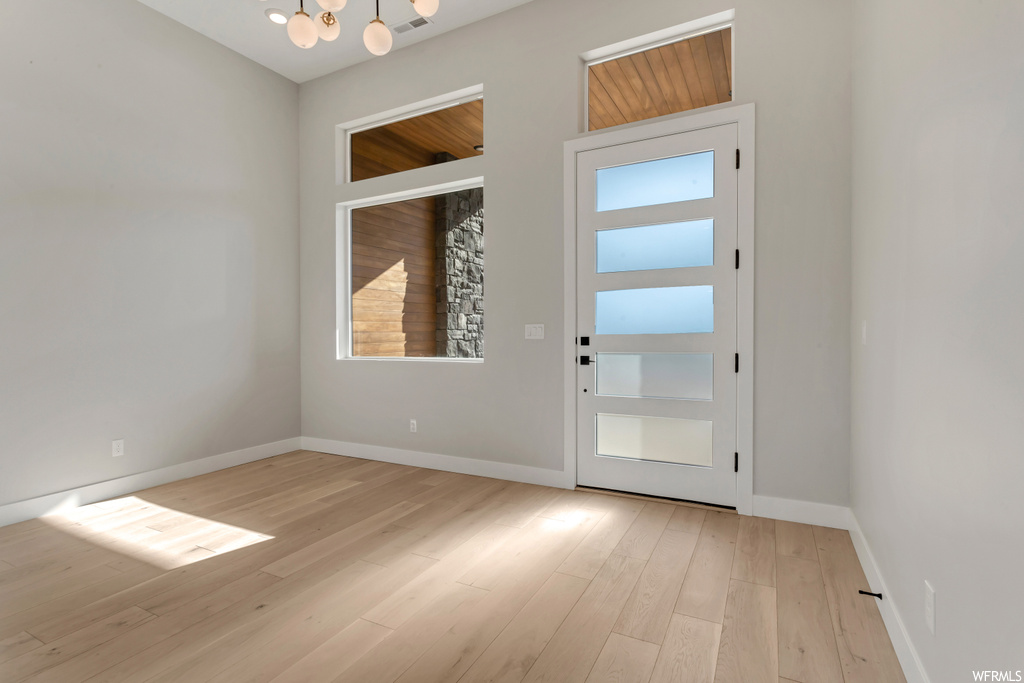 Doorway to outside featuring a notable chandelier and light hardwood / wood-style flooring