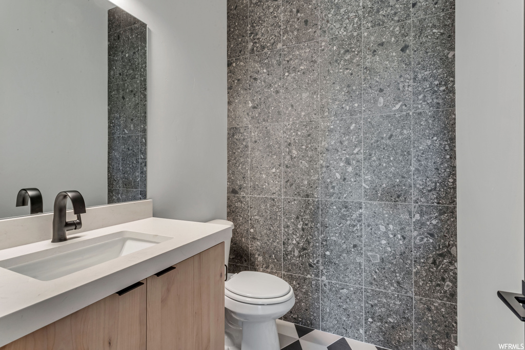 Bathroom featuring vanity, toilet, tile walls, and tile flooring
