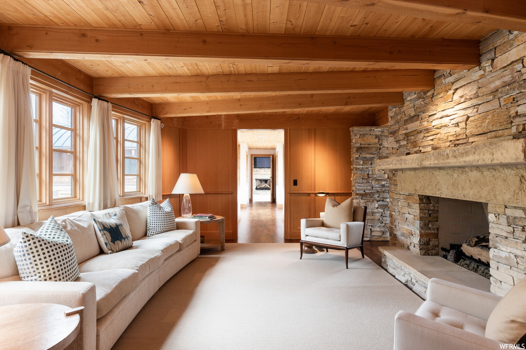 living room with carpet, a fireplace, beamed ceiling, and natural light
