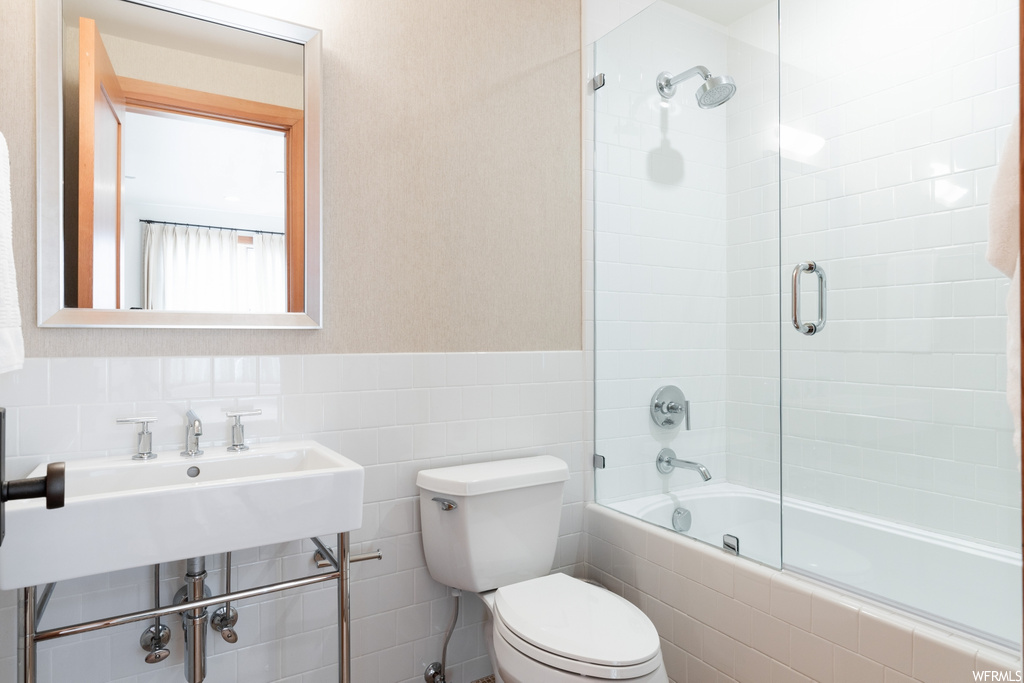 full bathroom featuring toilet, sink, bath / shower combo with glass door, and mirror
