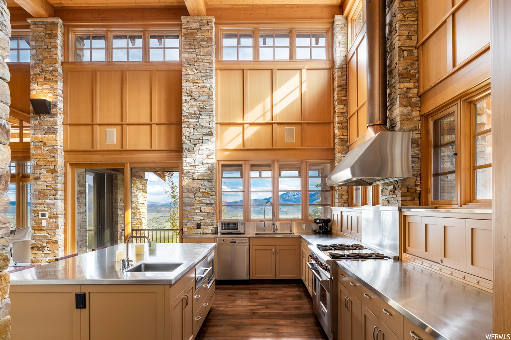 kitchen featuring natural light, hardwood flooring, fume extractor, gas range oven, stainless steel dishwasher, and brown cabinetry