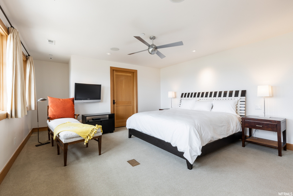 carpeted bedroom with a ceiling fan and TV