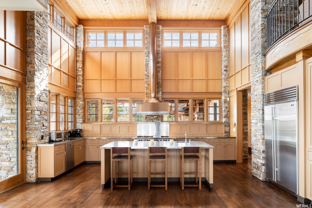 kitchen featuring natural light, a kitchen island, refrigerator, stainless steel dishwasher, dark hardwood flooring, and light countertops