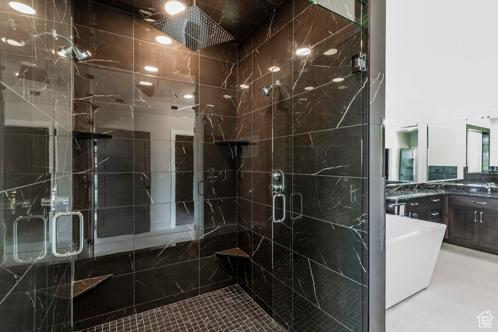 Bathroom featuring tile flooring, tile walls, a shower with shower door, and vanity