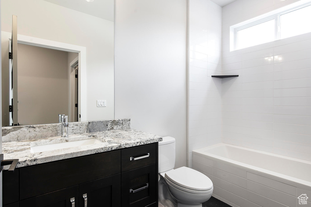 Full bathroom with oversized vanity, toilet, and tiled shower / bath combo