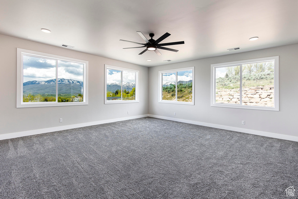 Empty room featuring carpet, a mountain view, and ceiling fan