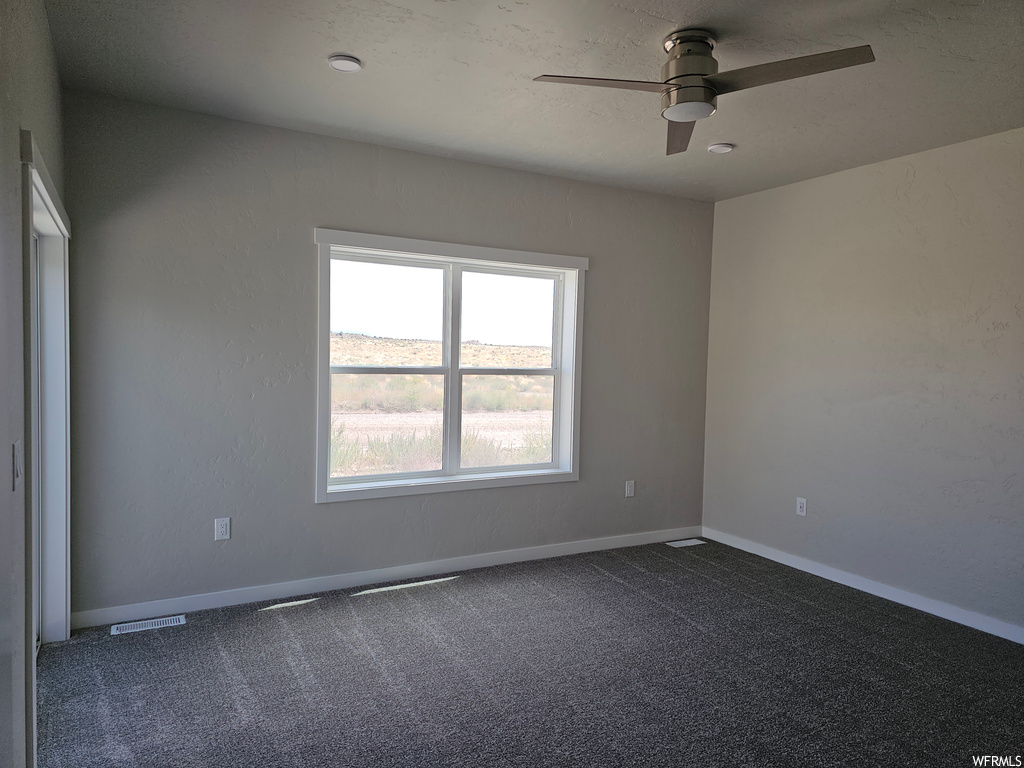 Empty room with ceiling fan and carpet flooring
