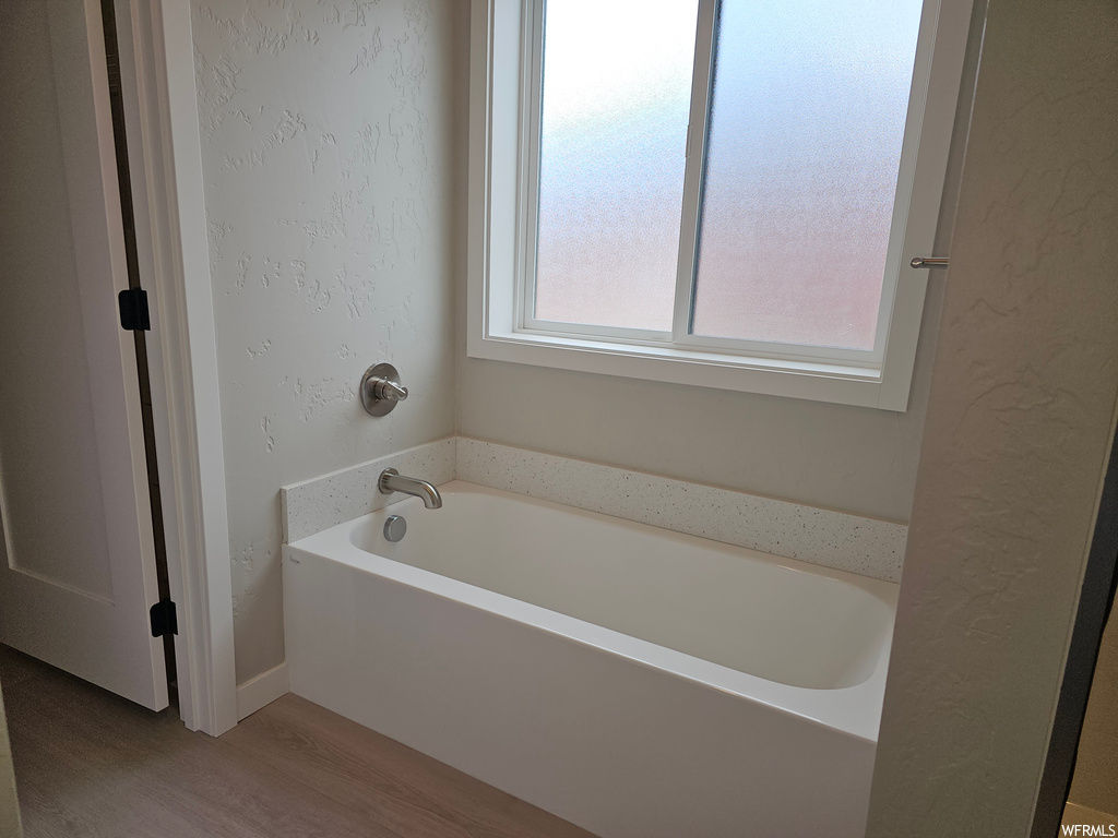 Bathroom with a tub and hardwood flooring