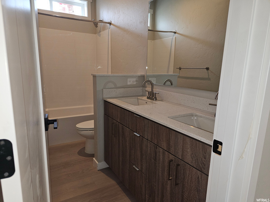 Full bathroom featuring hardwood floors, bathing tub / shower combination, double sink vanity, and mirror