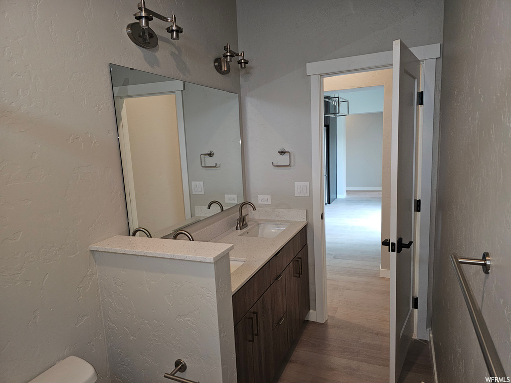 Bathroom featuring large vanity, mirror, and hardwood flooring