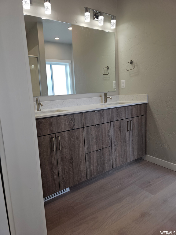 Bathroom with hardwood flooring, dual vanity, and mirror