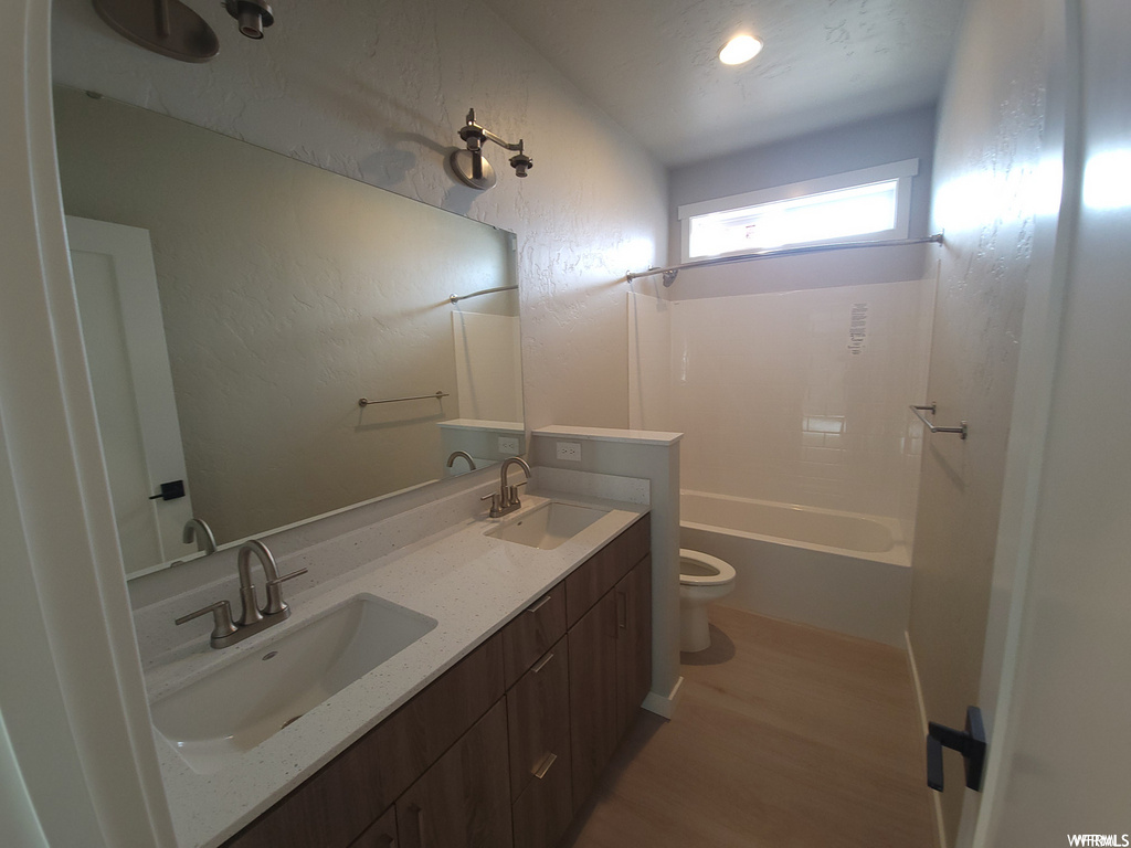 Full bathroom with natural light, toilet, mirror, shower / bath combination, and dual bowl vanity