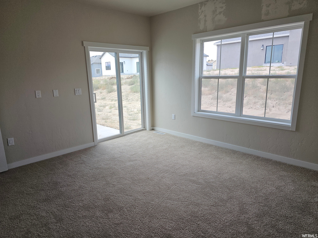 Empty room with a wealth of natural light and light carpet