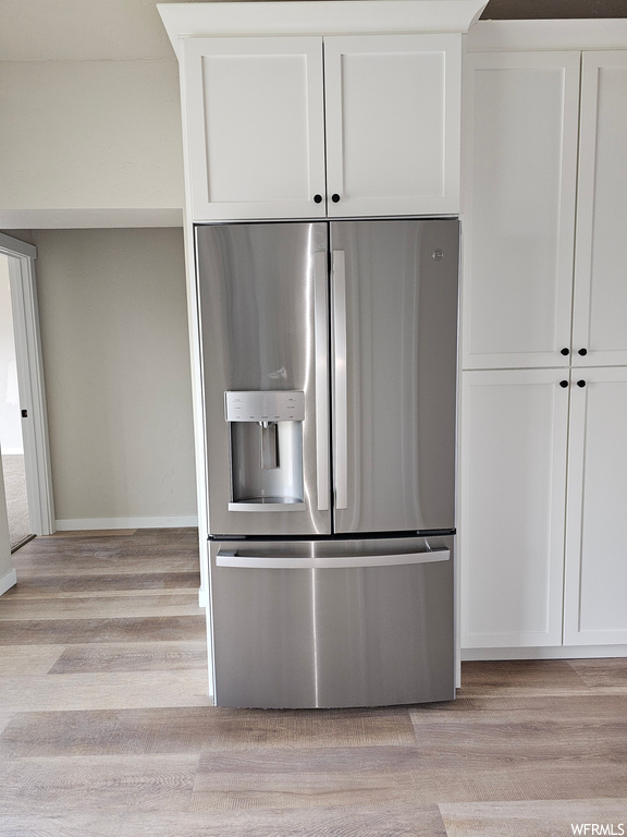 Kitchen featuring stainless steel refrigerator with ice dispenser and light hardwood floors