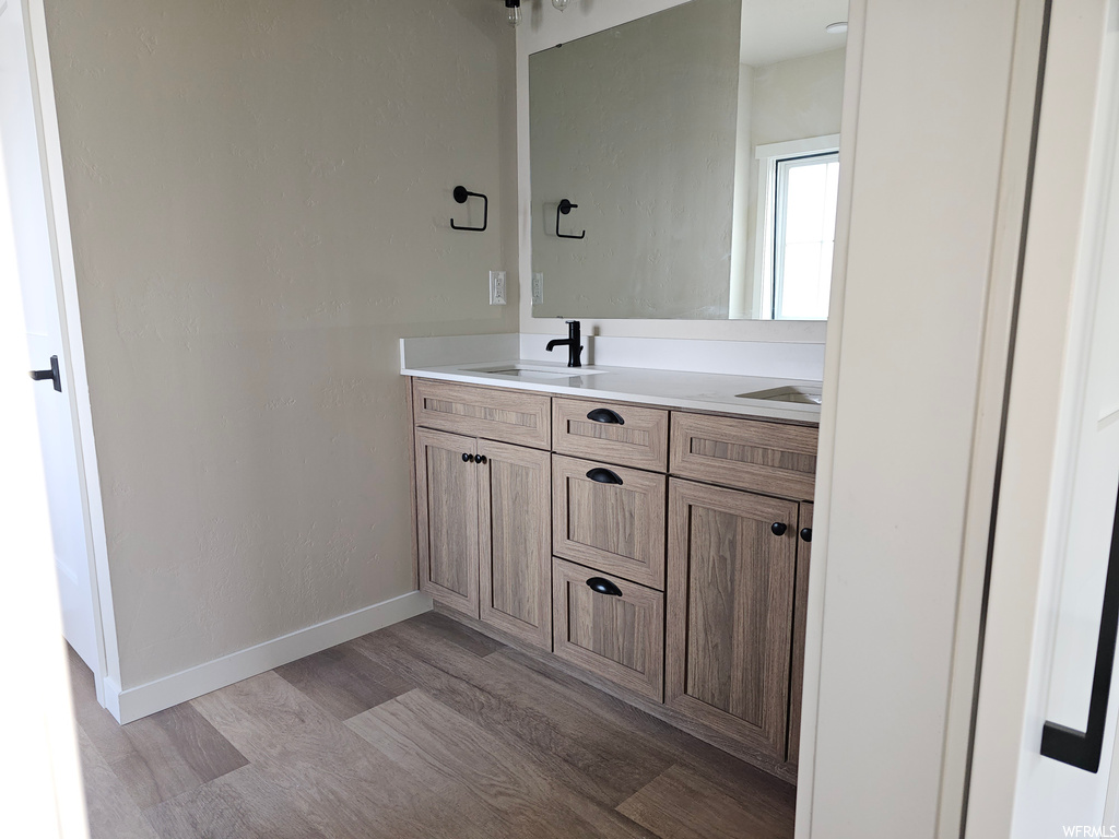 Bathroom featuring light hardwood flooring, dual vanity, and mirror
