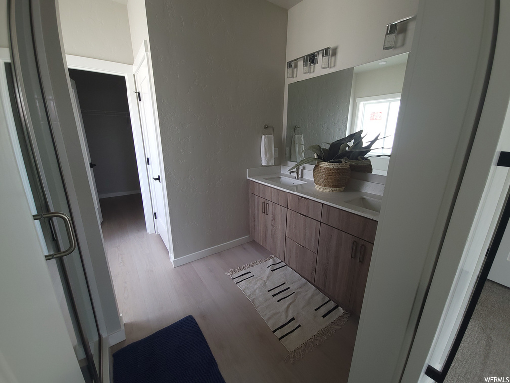 Bathroom featuring hardwood floors, natural light, mirror, and his and hers large vanity