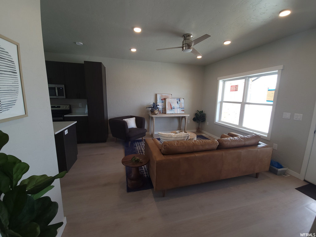 Living room with a ceiling fan, natural light, and microwave