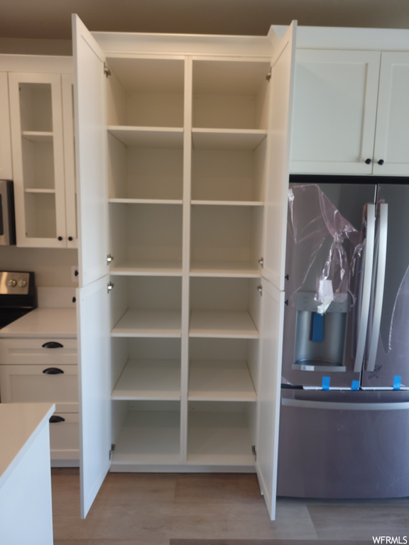 Pantry with hardwood floors and microwave