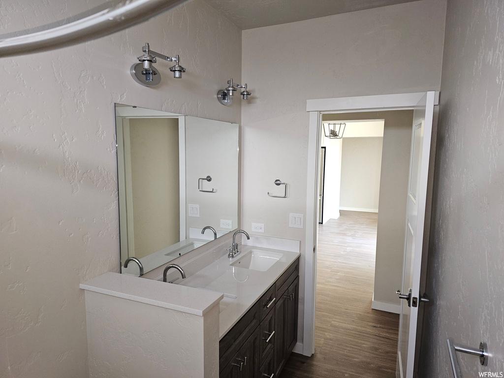 Bathroom with mirror, vanity with extensive cabinet space, and hardwood floors