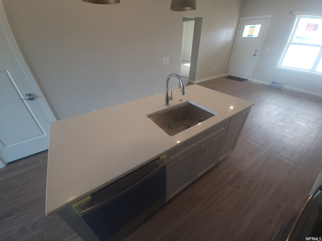 Kitchen with natural light, dishwasher, dark hardwood floors, and kitchen island sink