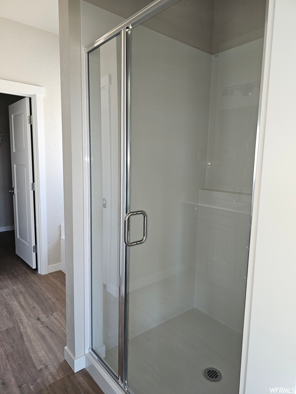 Bathroom featuring an enclosed shower and dark hardwood flooring