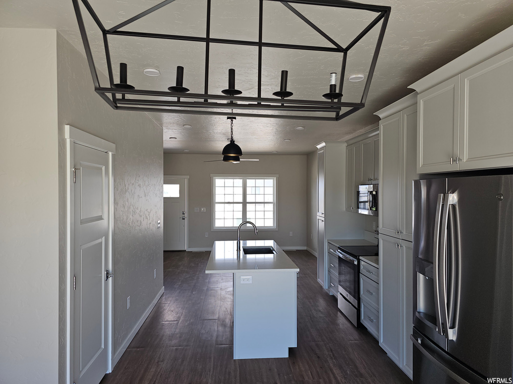 Kitchen with hanging light fixtures, appliances with stainless steel finishes, ceiling fan, and dark hardwood floors
