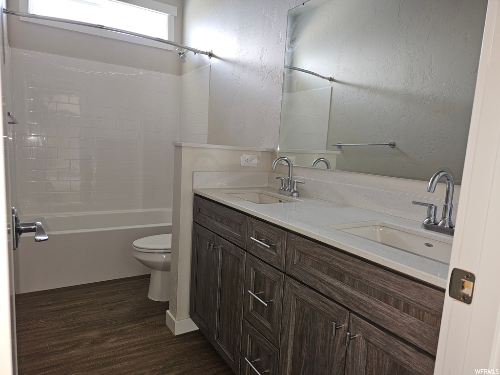 Full bathroom with mirror, shower / bathing tub combination, hardwood flooring, and double vanity