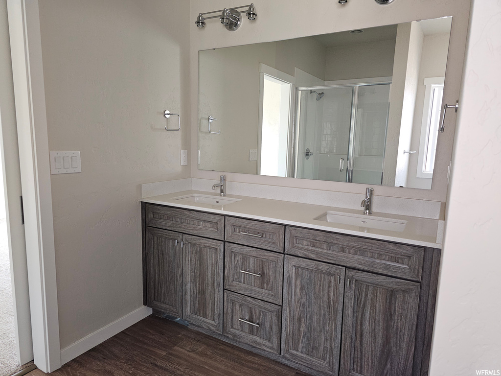 Bathroom with hardwood flooring, dual large vanity, an enclosed shower, and mirror