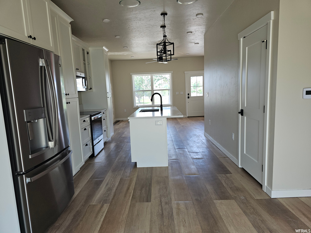 Kitchen with stainless steel appliances, wood-type flooring, and hanging light fixtures