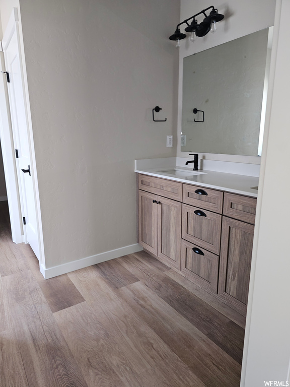 Bathroom with light hardwood floors, mirror, and vanity