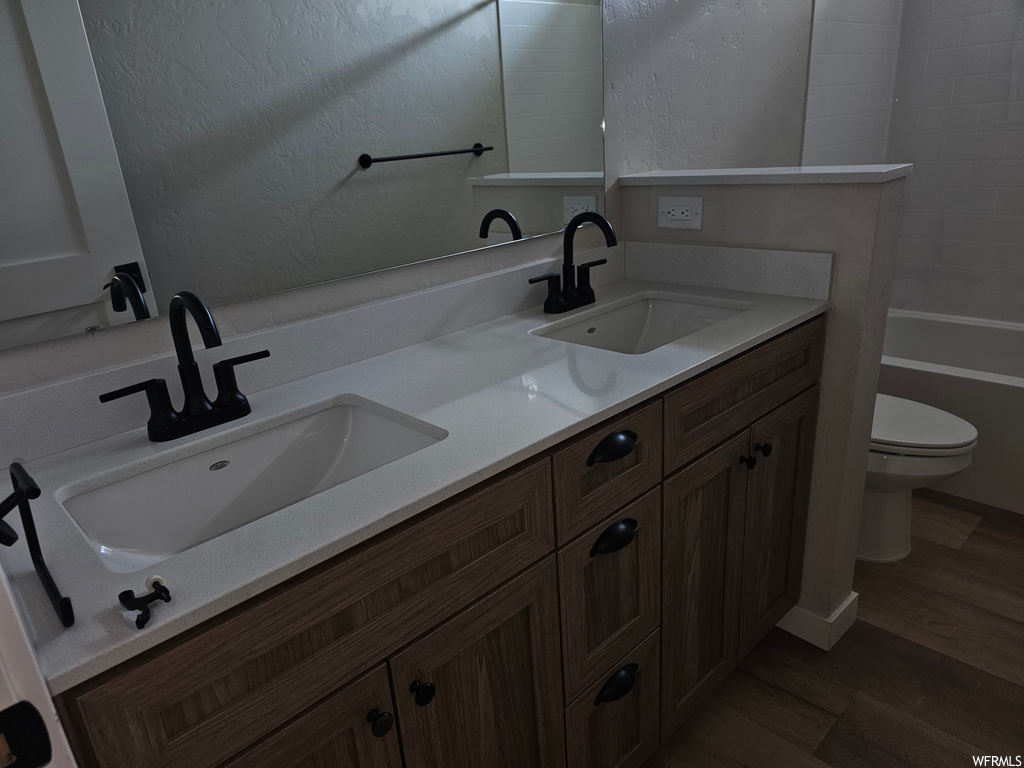 Bathroom with dark hardwood flooring, double large sink vanity, and mirror