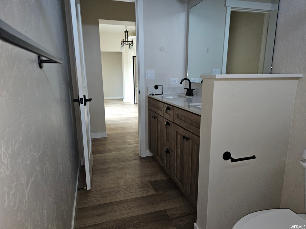 Bathroom with dark hardwood flooring, mirror, and vanity