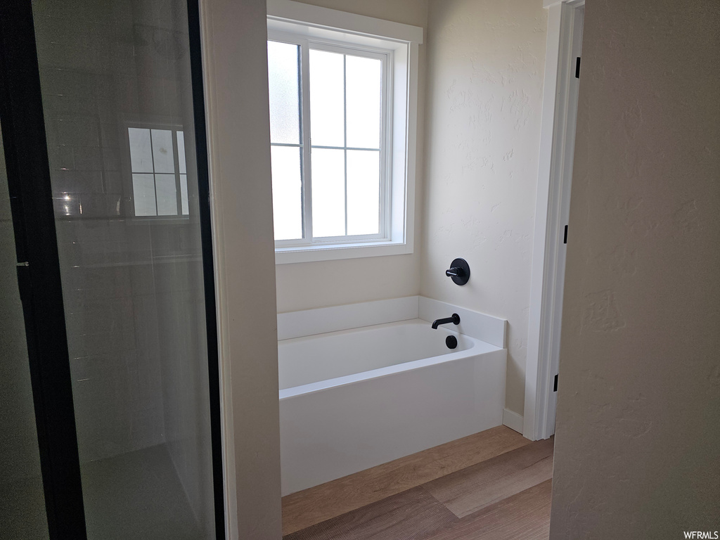 Bathroom featuring plenty of natural light, a bathing tub, and hardwood floors