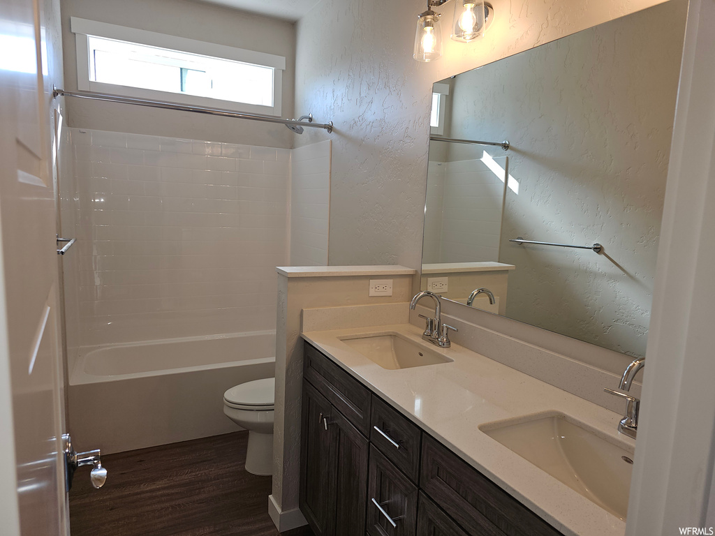 Full bathroom with mirror, dark parquet floors, shower / bathing tub combination, and dual bowl vanity