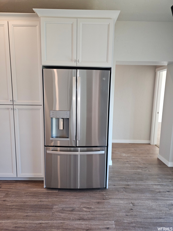 Kitchen with light hardwood floors and stainless steel refrigerator with ice dispenser