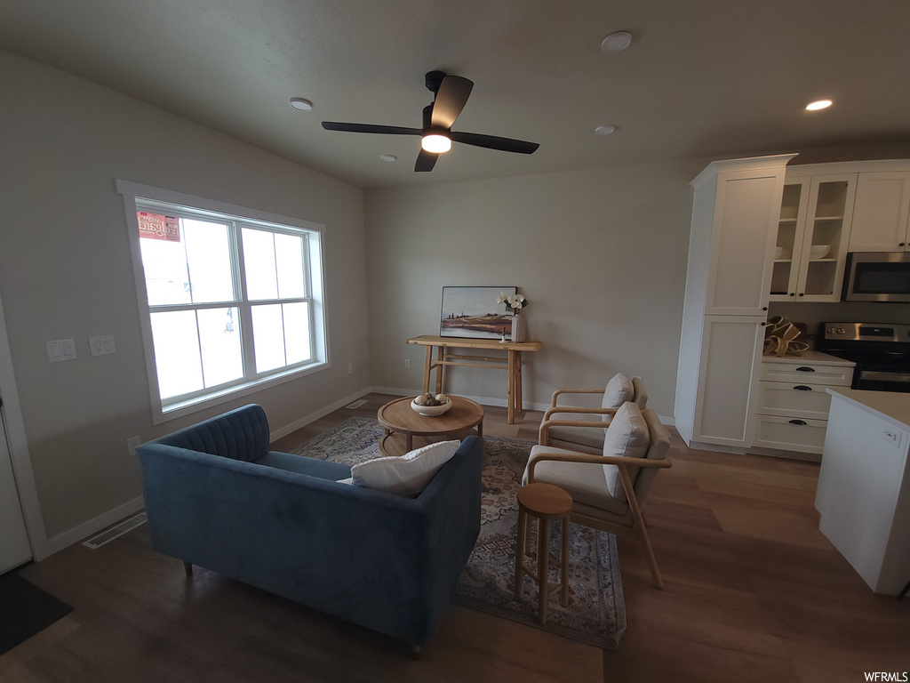 Living room with natural light, hardwood flooring, a ceiling fan, and microwave