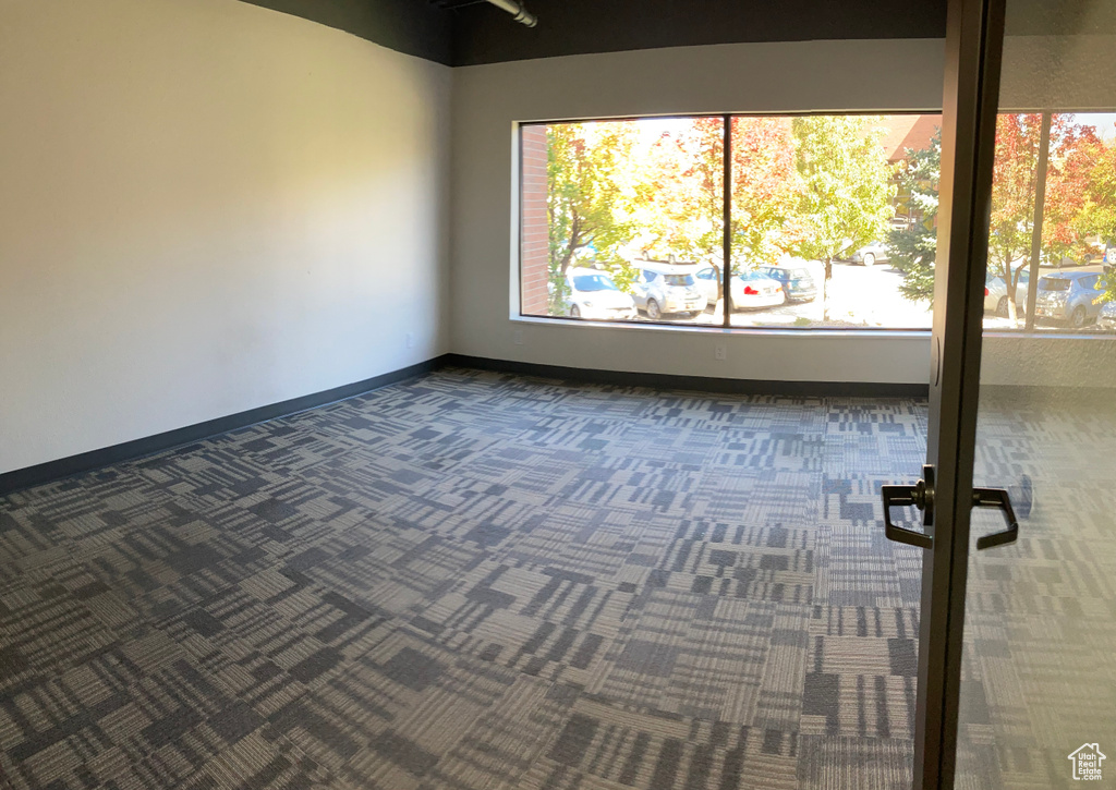 Unfurnished room with dark colored carpet and healthy amount of natural light