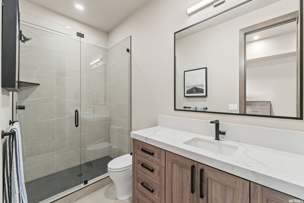 Bathroom featuring a shower with shower door, mirror, and vanity
