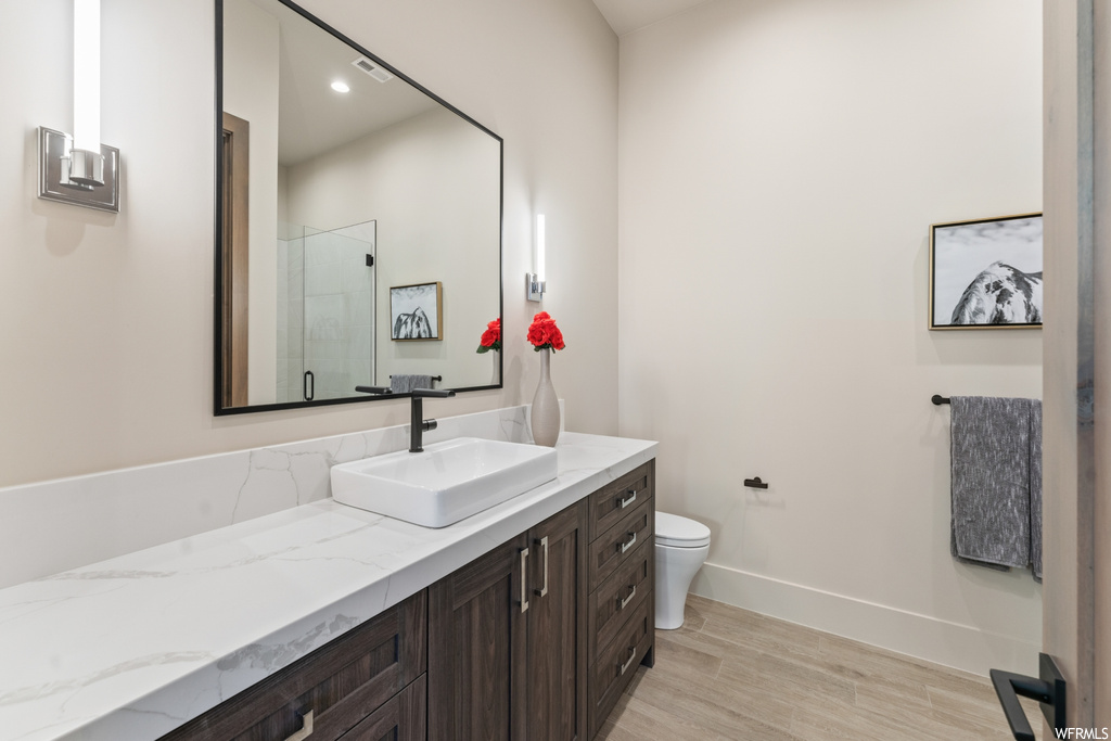 Bathroom featuring vanity with extensive cabinet space, mirror, and light hardwood floors