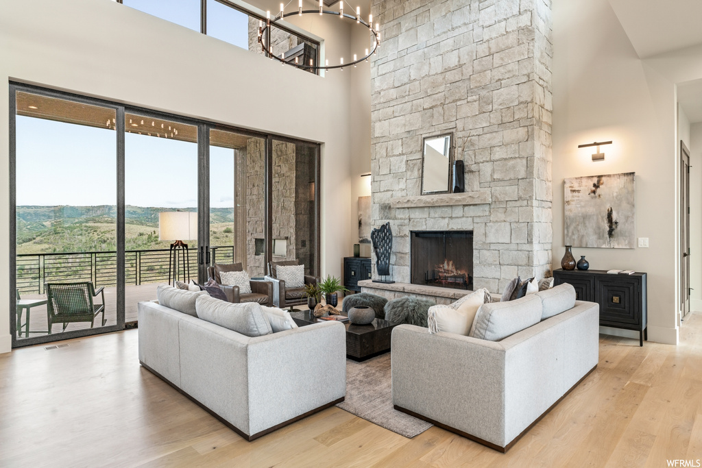 Living room featuring a fireplace, light hardwood flooring, plenty of natural light, and a high ceiling