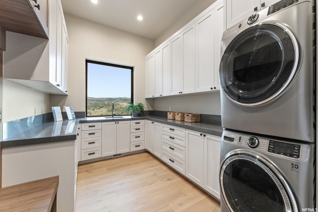Laundry area featuring stacked washer and clothes dryer and light hardwood floors