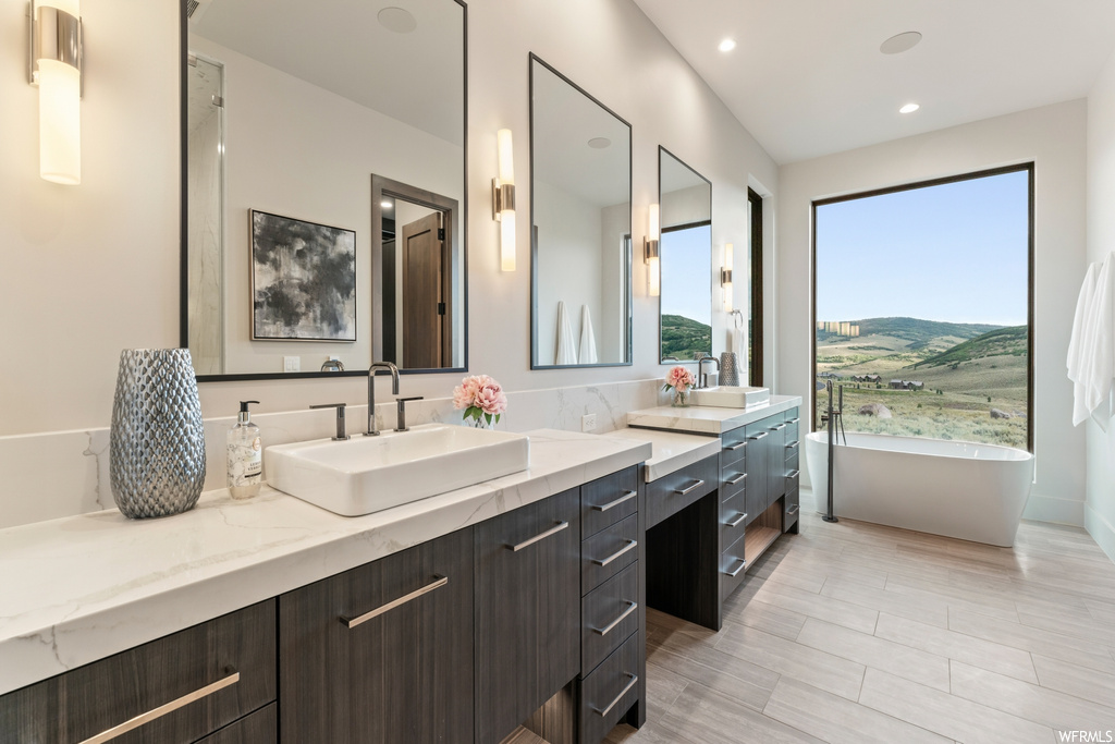 Bathroom with dual vanity, a wealth of natural light, mirror, and light tile floors