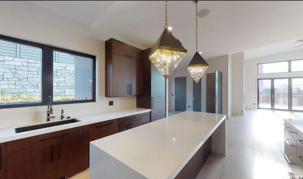 kitchen featuring natural light, pendant lighting, dark brown cabinets, light countertops, and light floors